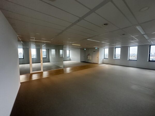 Leeg kantoorpand aan de Laan van Zuid Hoorn met grote ramen, glazen tussenwand en uitzicht op de stad.